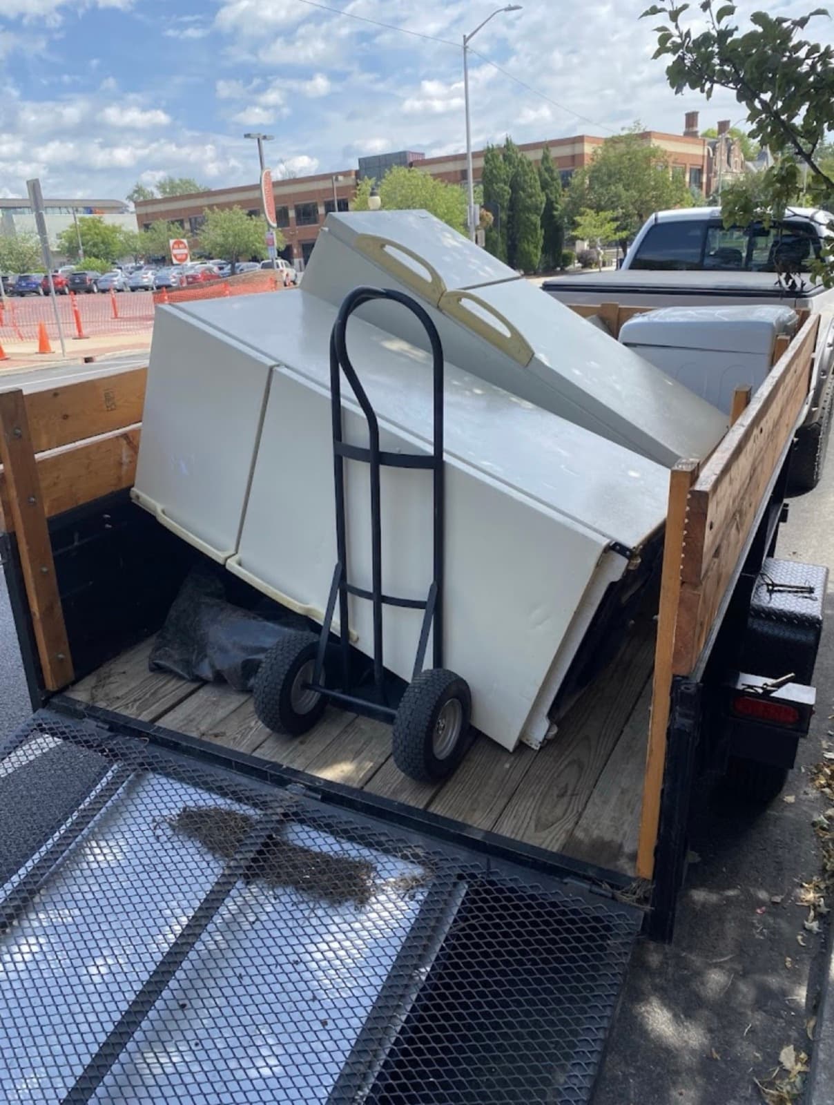 Chest freezers and a hand truck loaded on the trailer's wood deck, ramp gate down — The Junk Lord, York County