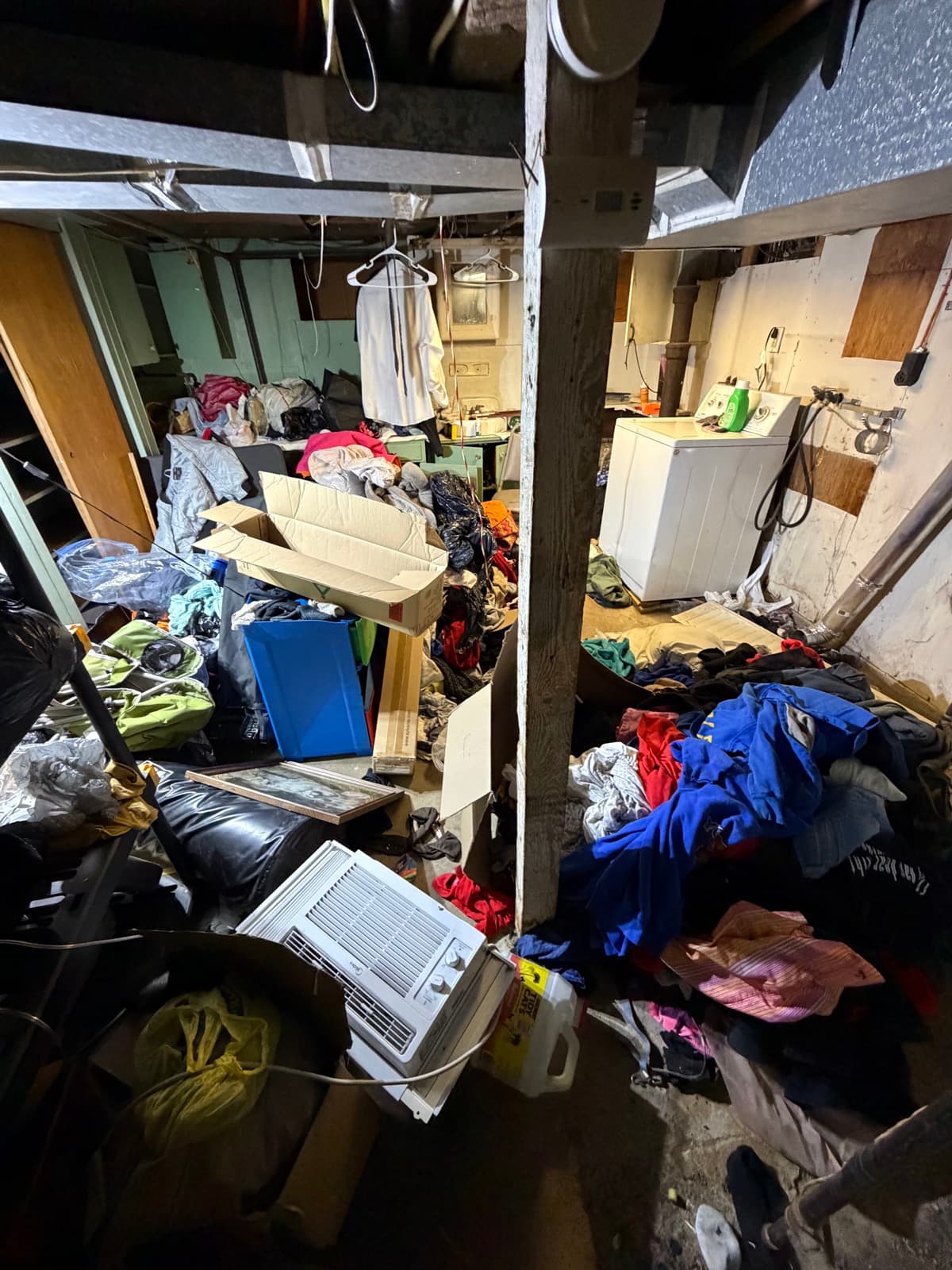 Hoarder basement piled wall-to-wall with bagged clothing, household goods, and salvage furniture — partway through a Junk Lord cleanout in York County, PA