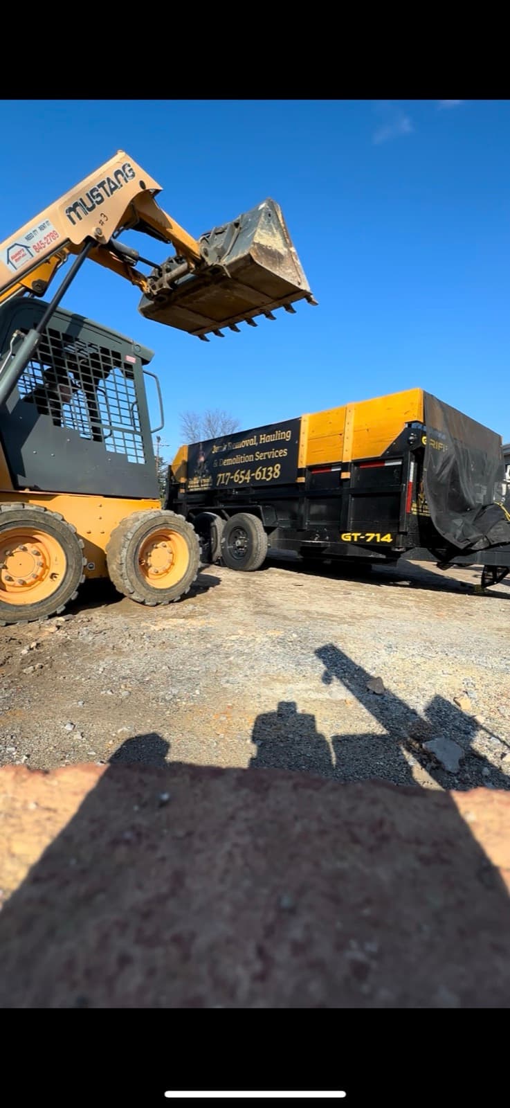 Junk Lord mini-skid loader and branded trailer staged for a construction debris haul — York County, PA
