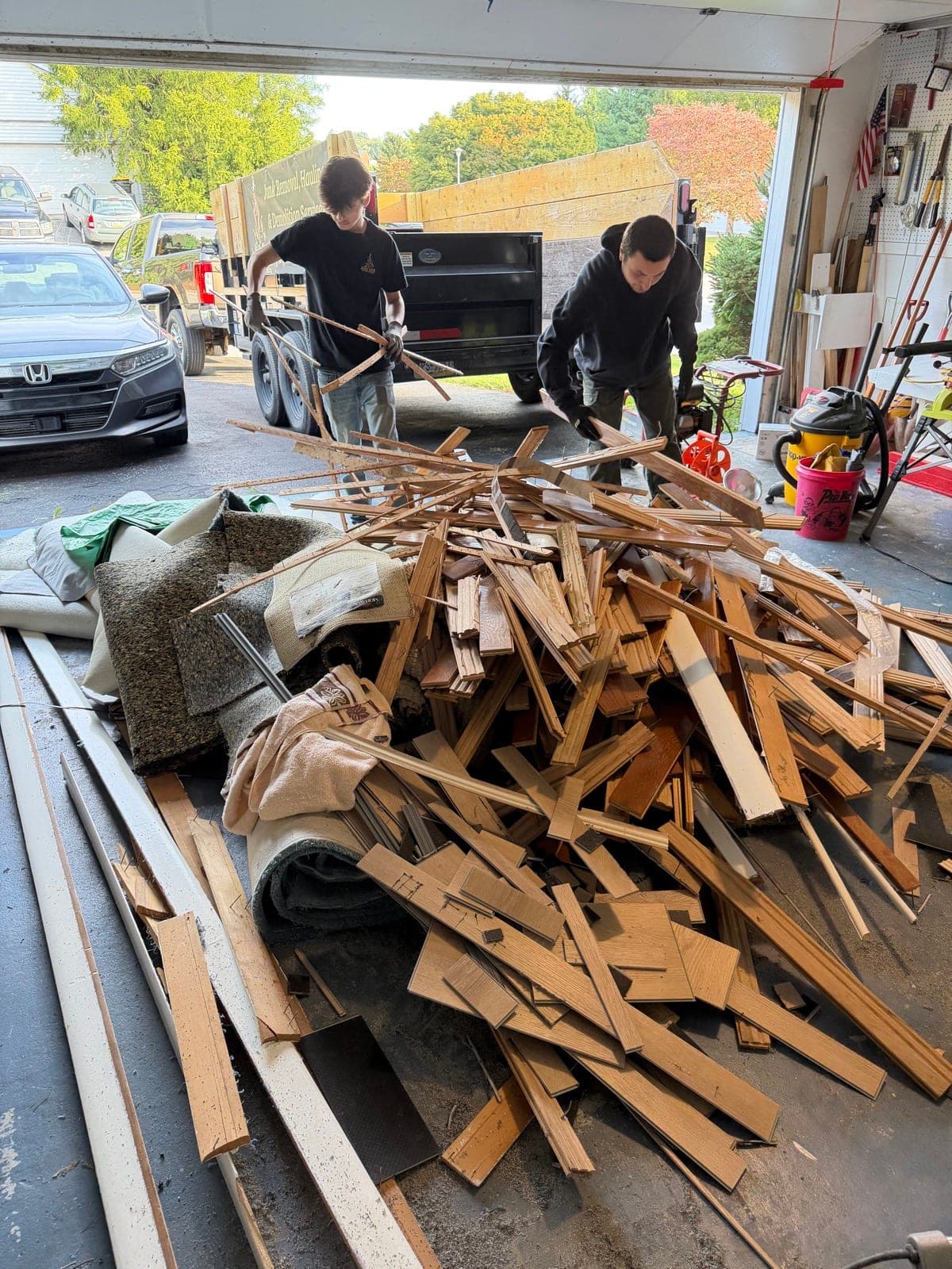 Junk Lord crew clearing stacked hardwood flooring from a residential garage in York County, PA