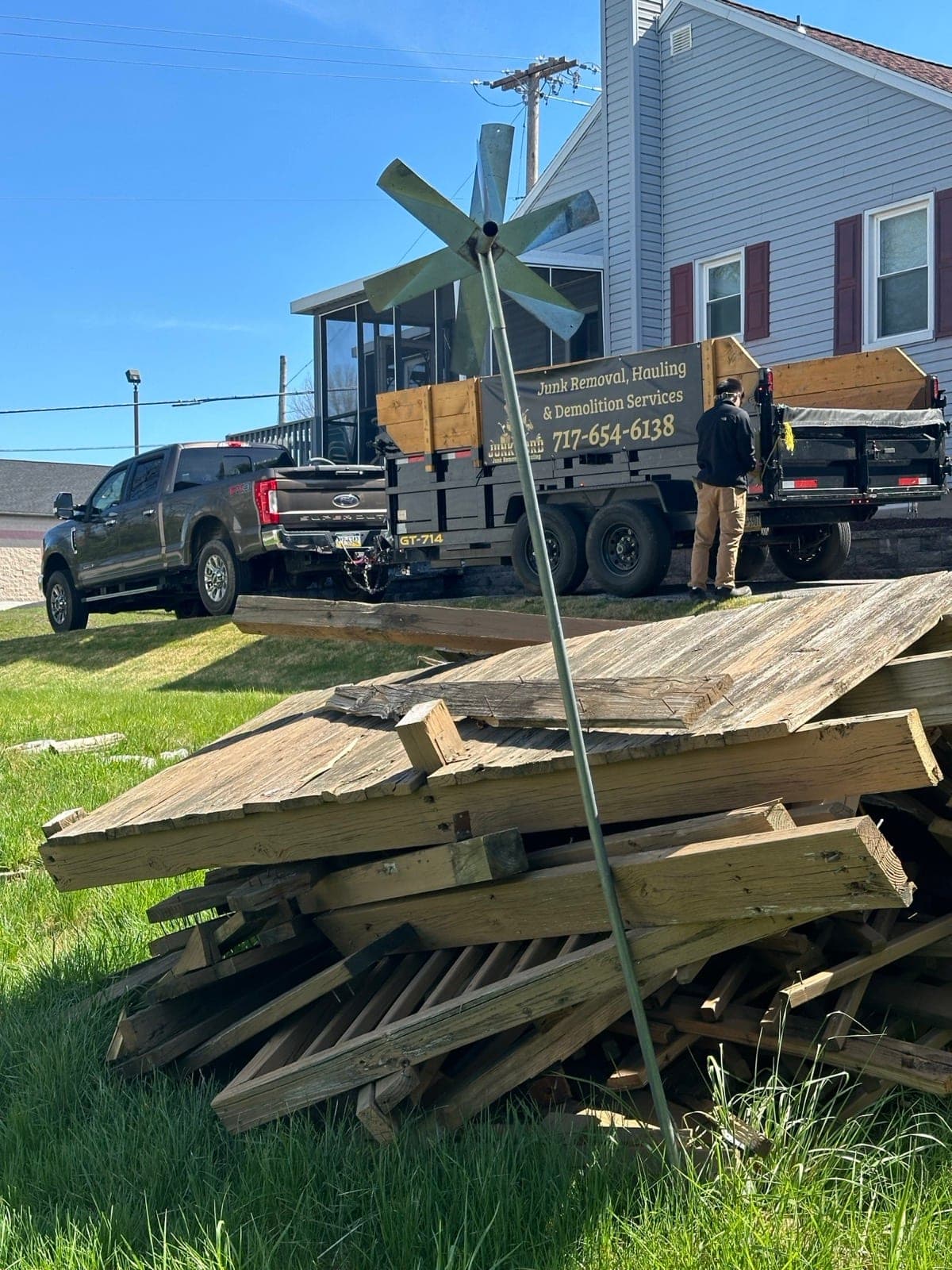 Branded Junk Lord trailer with stacked deck boards next to a York County, PA home