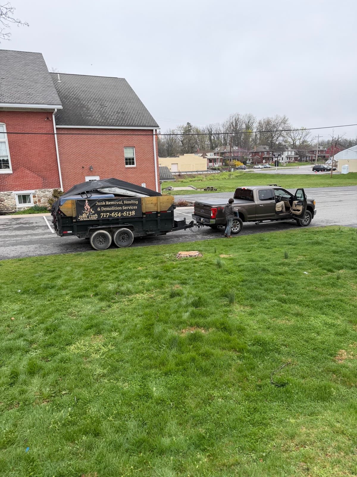 Branded Junk Lord dump trailer hitched to the company pickup, staged on grass at a York County, PA brick home