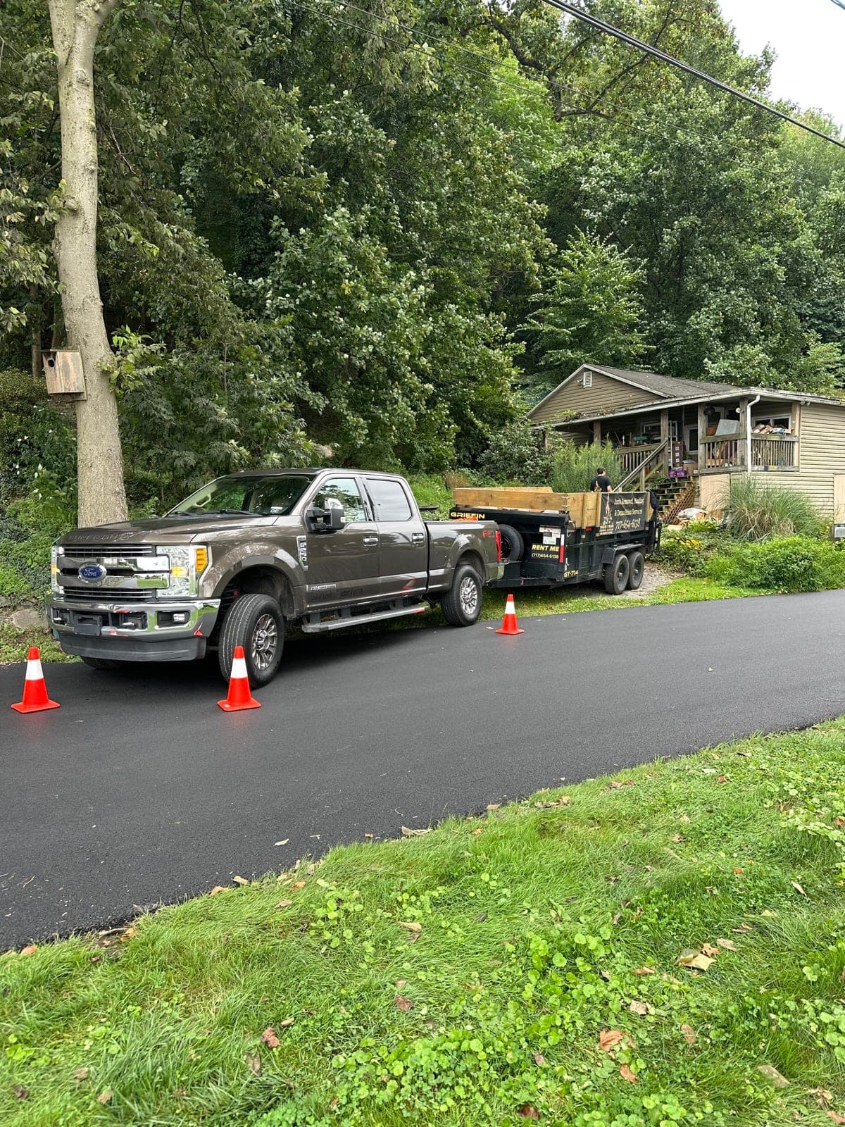 Junk Lord pickup and dump trailer parked in a York County, PA driveway with safety cones set around the rig