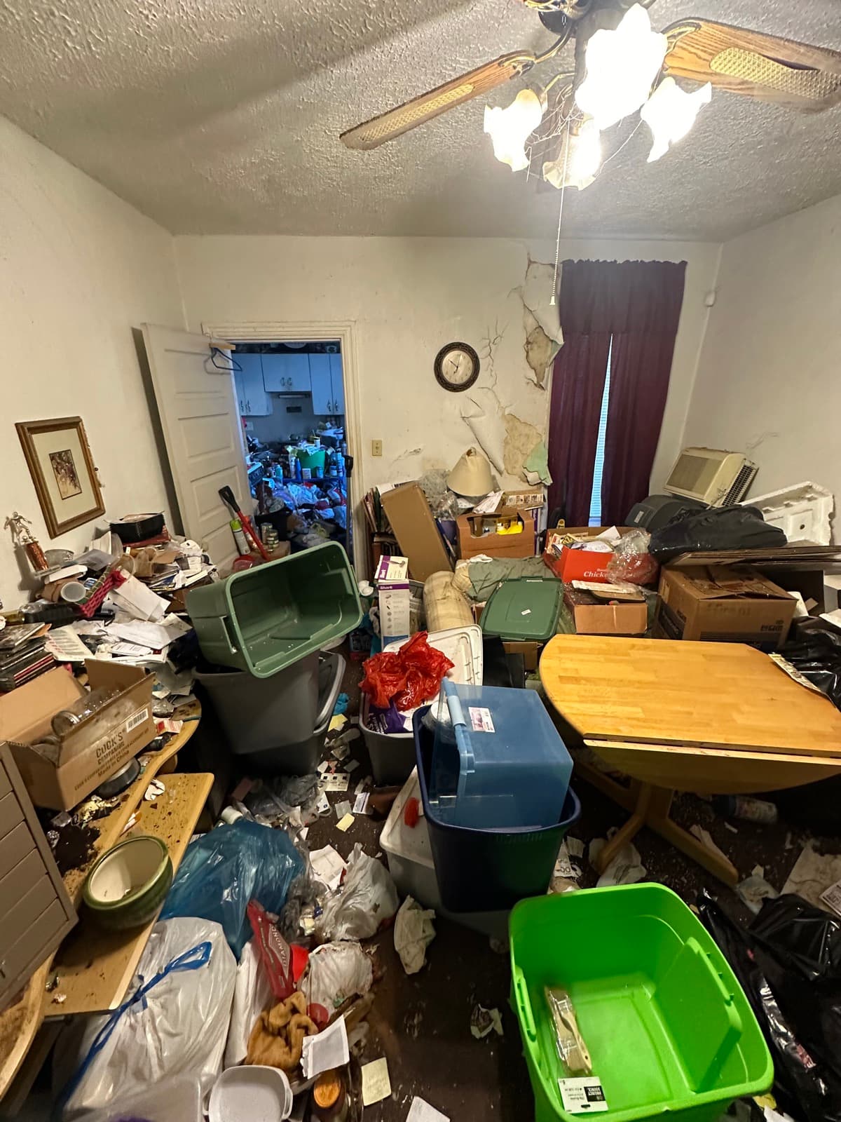 Second angle of a hoarder kitchen in York County, PA showing green totes, mounded bags, and a blocked walking path