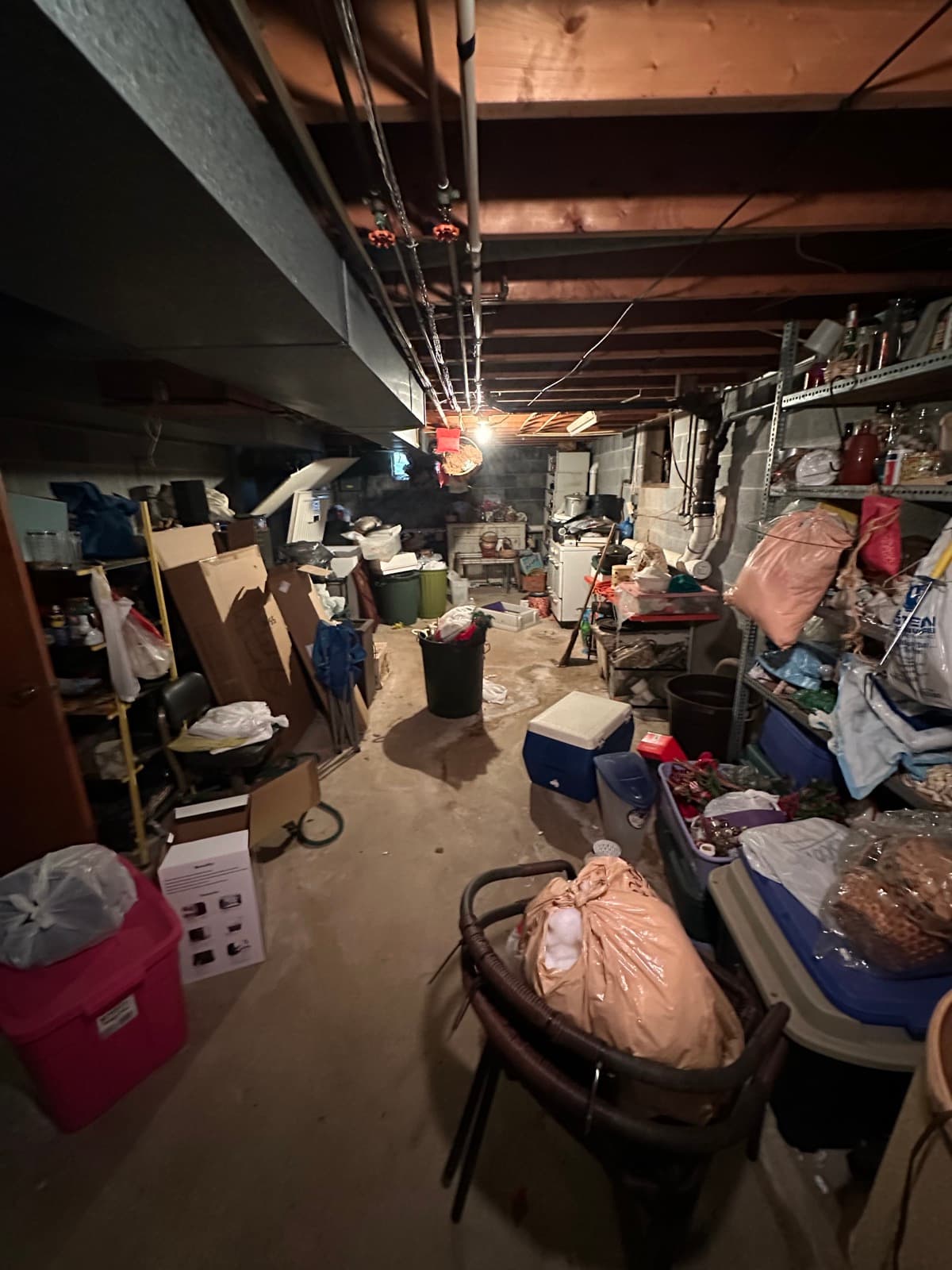 Hoarder basement in York County, PA packed wall-to-wall with bagged clutter, totes, and salvage furniture — pre-cleanout shot