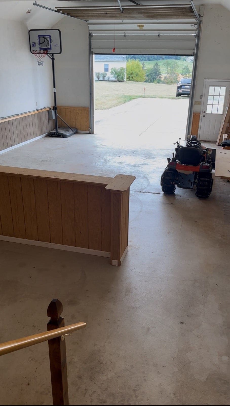 Cleared garage in York County, PA with the wood bar, basketball hoop, and rider mower visible — The Junk Lord finished walkout