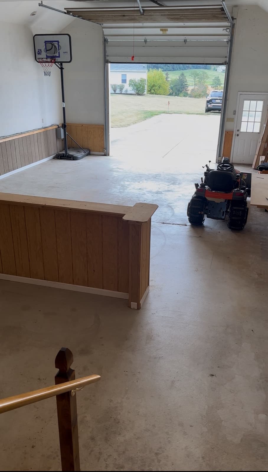 Cleared garage in York County, PA with the wood bar, basketball hoop, and rider mower visible — The Junk Lord finished walkout