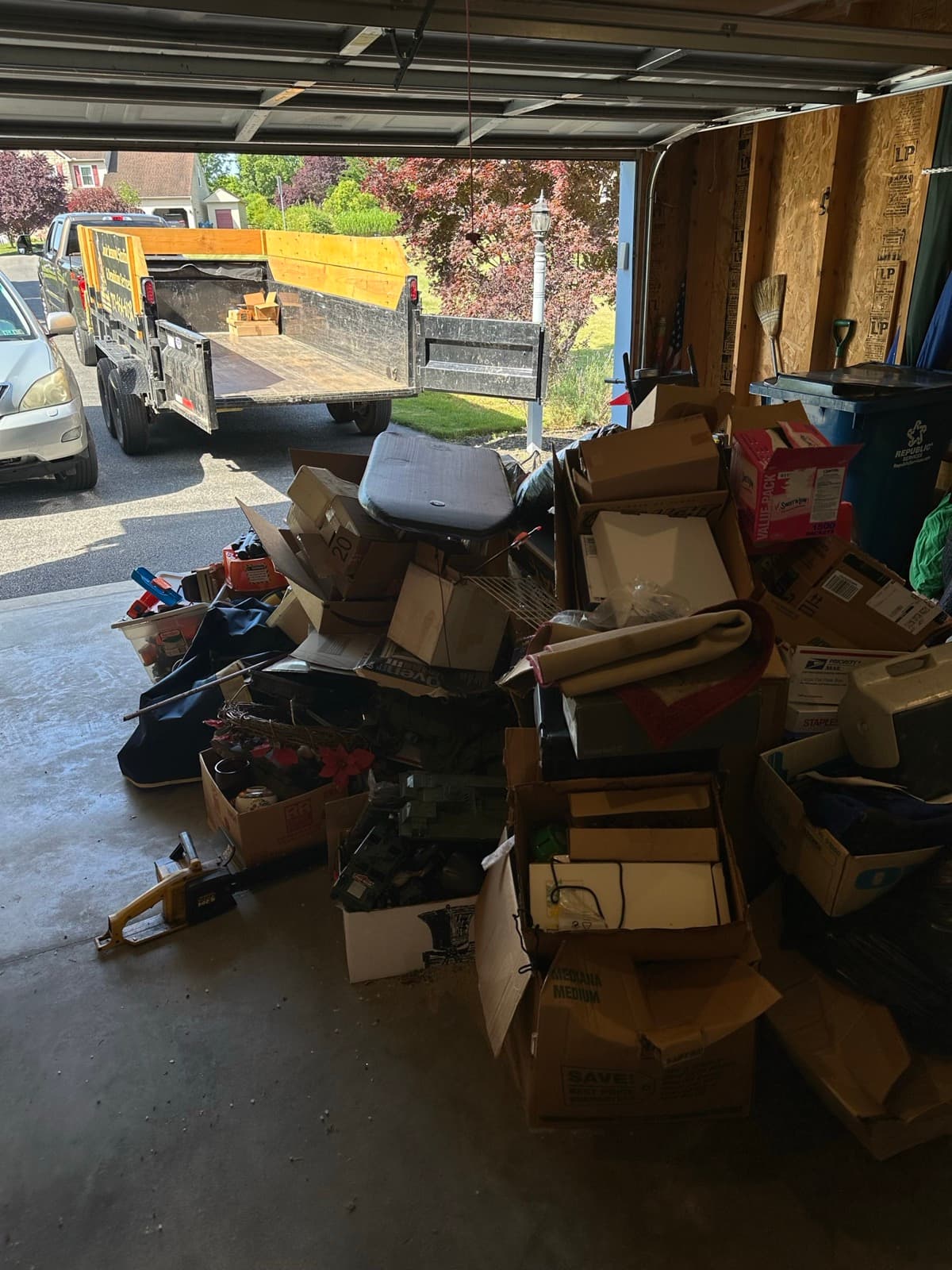 Open boxes, a rolled rug, and a cooler covering the garage floor mid-sort — The Junk Lord, York County PA