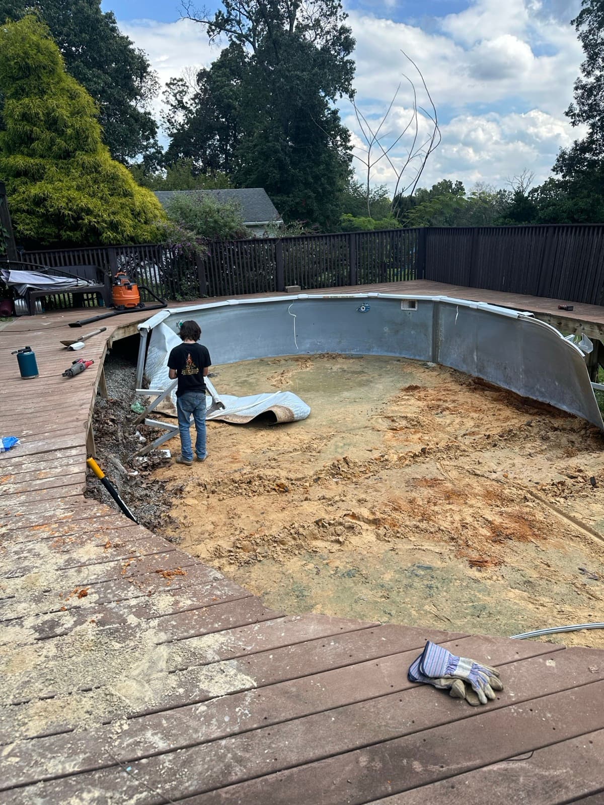 Worker inside a drained above-ground pool with the liner peeled back to the sand floor — The Junk Lord, York County PA